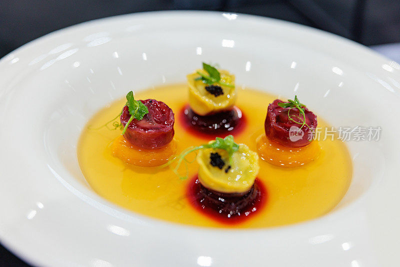 Close-up on pumpkin with walnut and gorgonzola tortellini in mushroom consommé